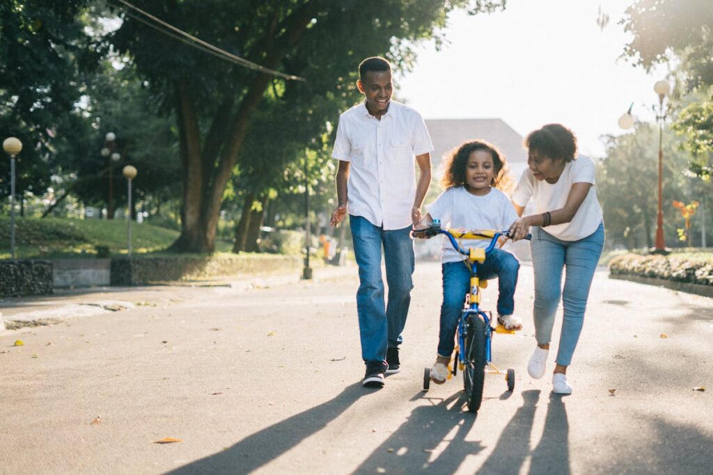 Man Standing Beside His Wife Teaching Their Child How to Ride Bicycle